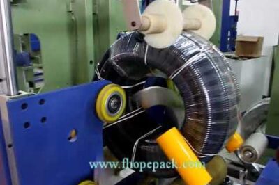 Compact film packing machine for corrugated hose coils.