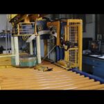 Compact packaging machine for coiled rolls.